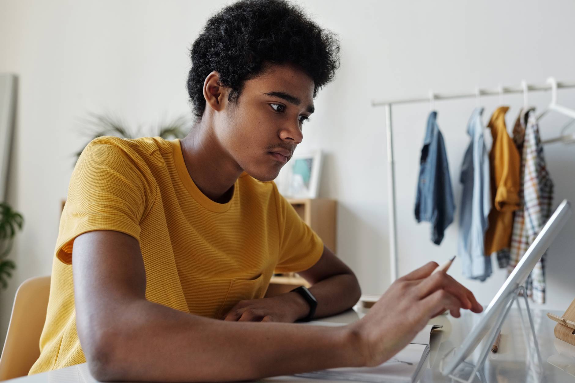 man in yellow crew neck t shirt while using tablet